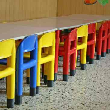 A row of brightly coloured chairs at a table in a nursery.