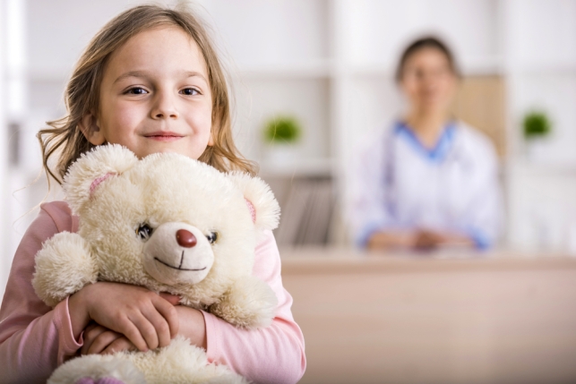 Child holding a teddy bear with nurse