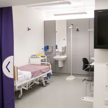 A medical examination room with bed, sink and medical equipment.