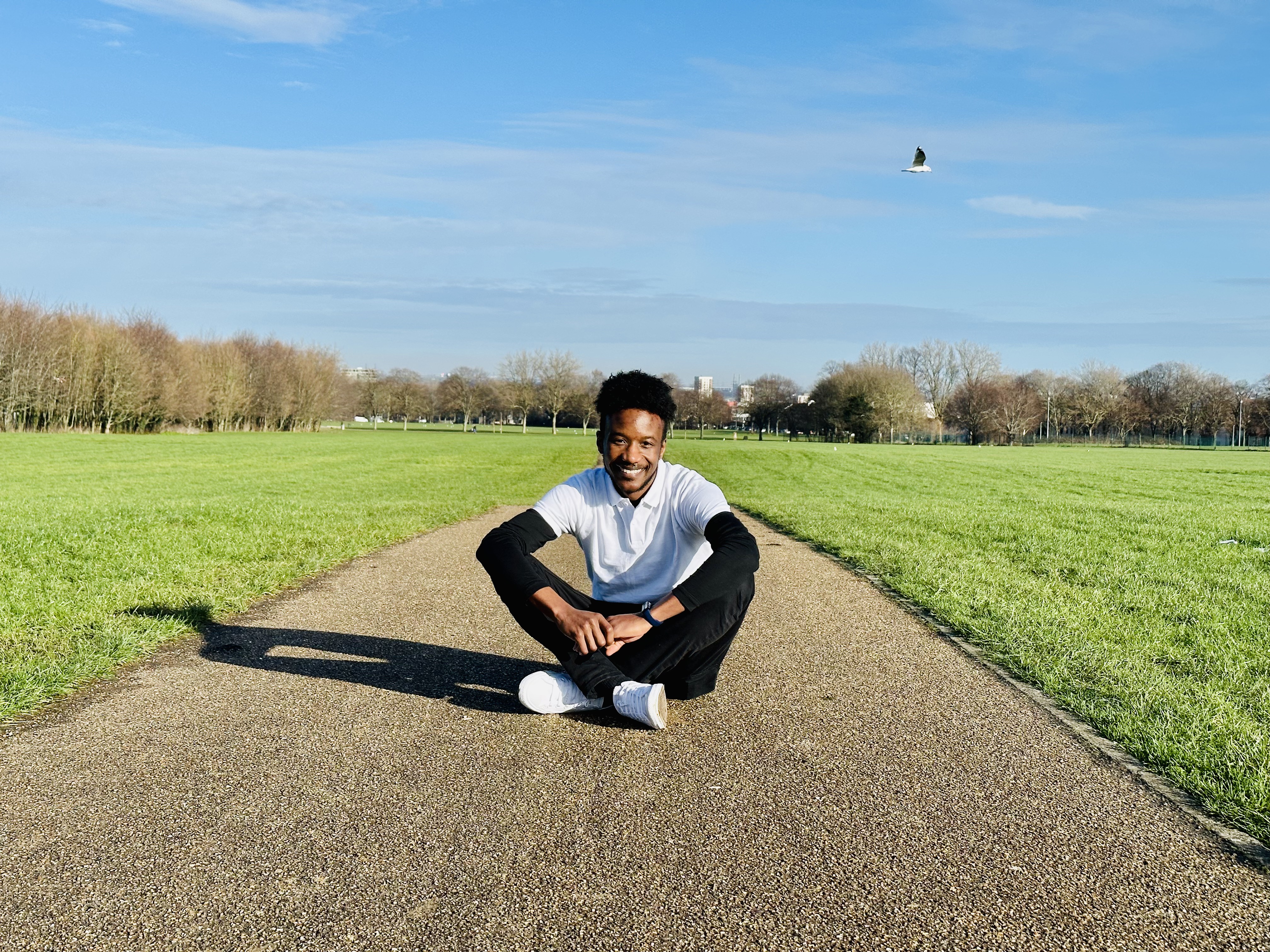 Joshua Muhumuza sitting on path in a park